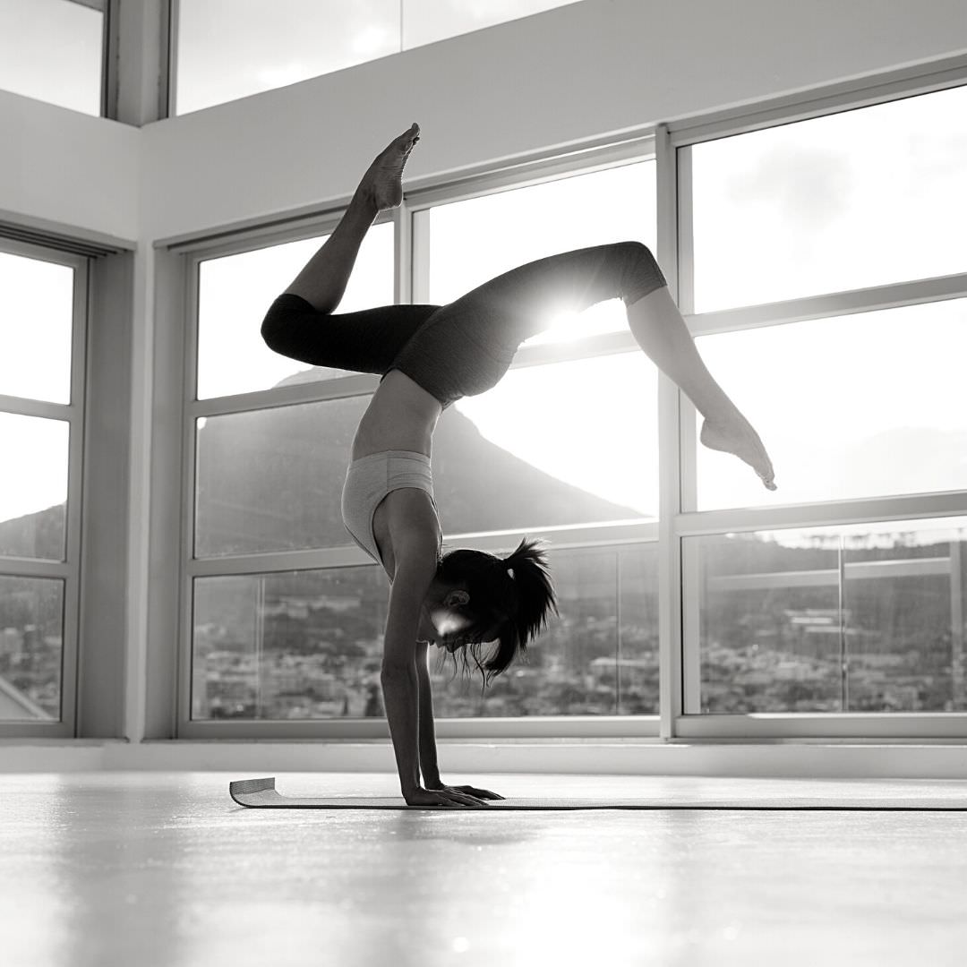 Woman doing handstand yoga pose. Online yoga teacher training certification reviews.