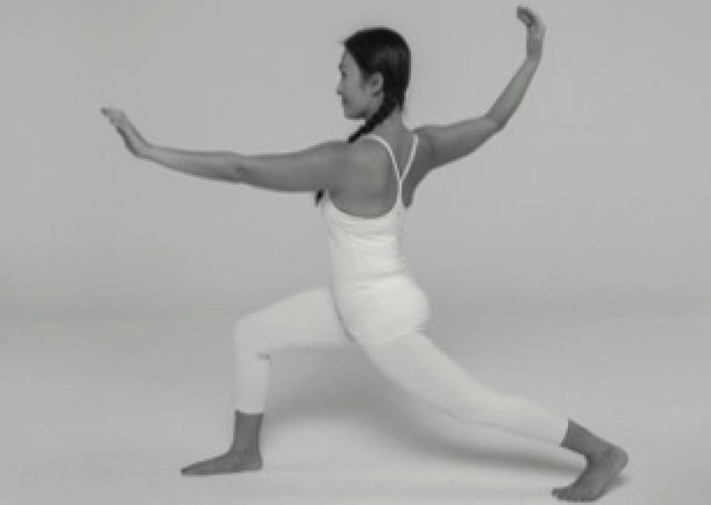 Woman lunging with one leg forward and bent doing Yin yoga dragon pose.