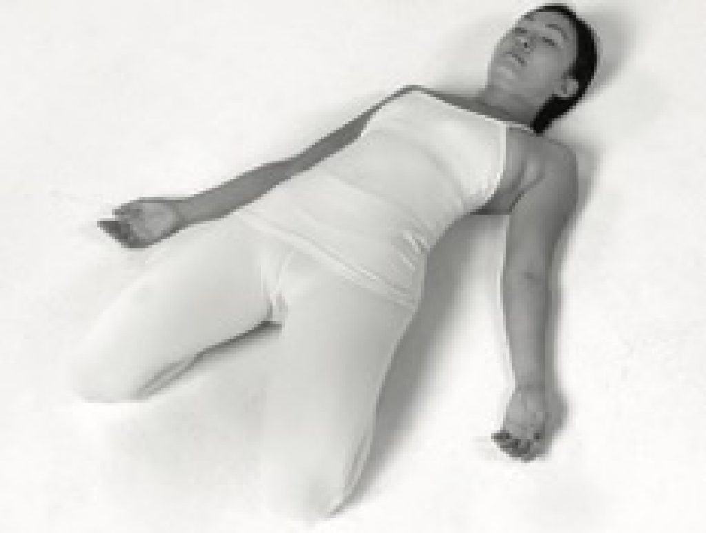 Woman lying on her back doing Yin yoga saddle pose.