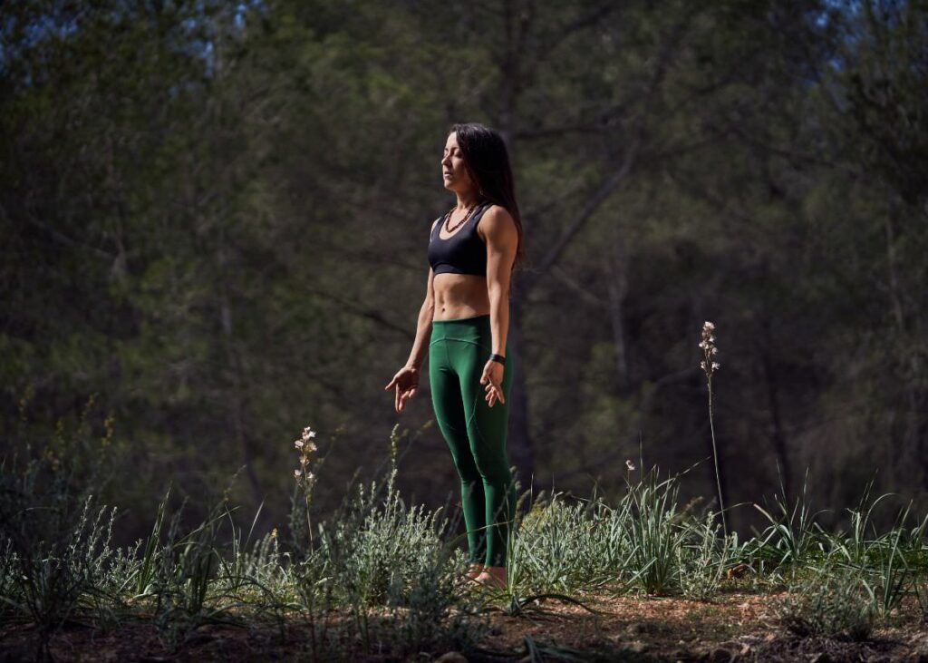 Brunette woman outside in nature practicing the standing posture, Mountain pose.