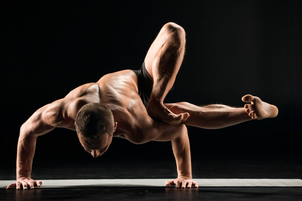 Man practicing Power yoga in in grasshopper yoga pose.