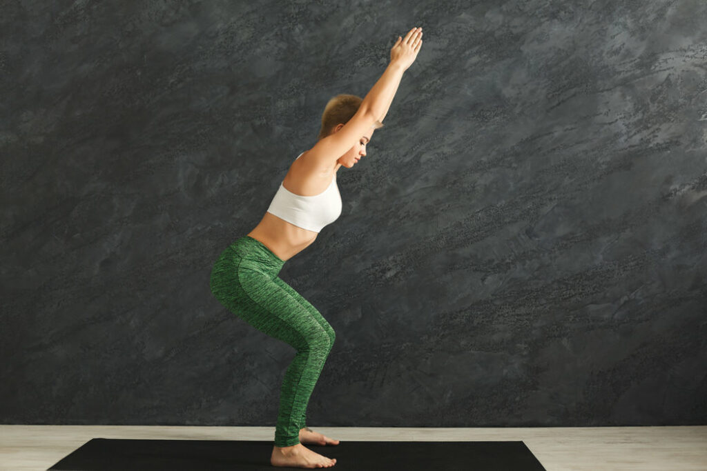 Female yogi practicing yoga in Chair Pose.