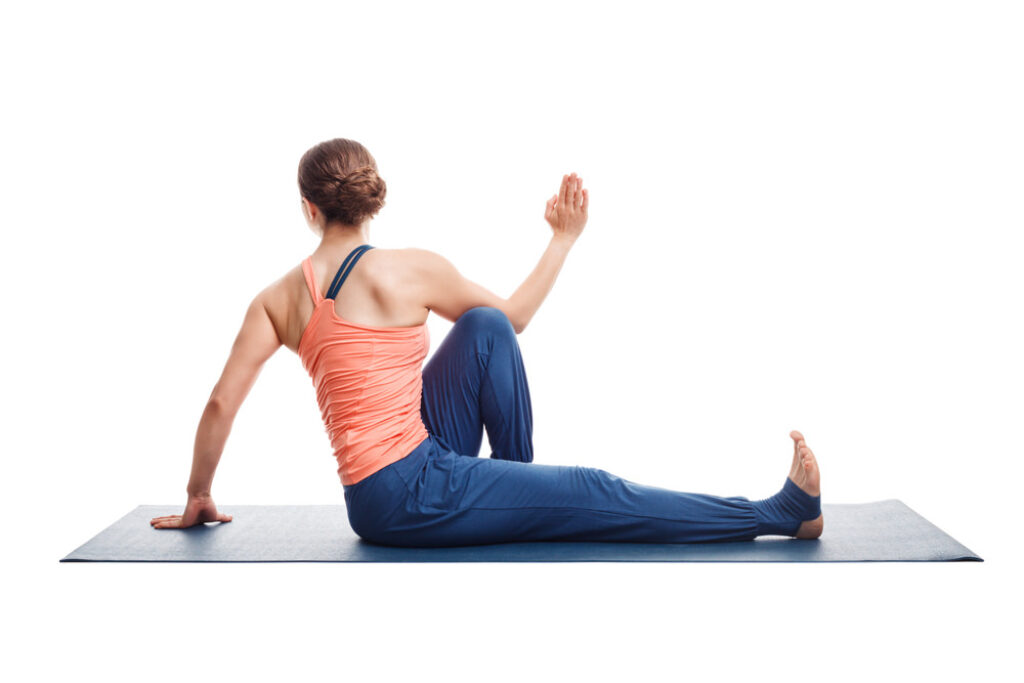 Female practicing yoga in spinal twist pose.