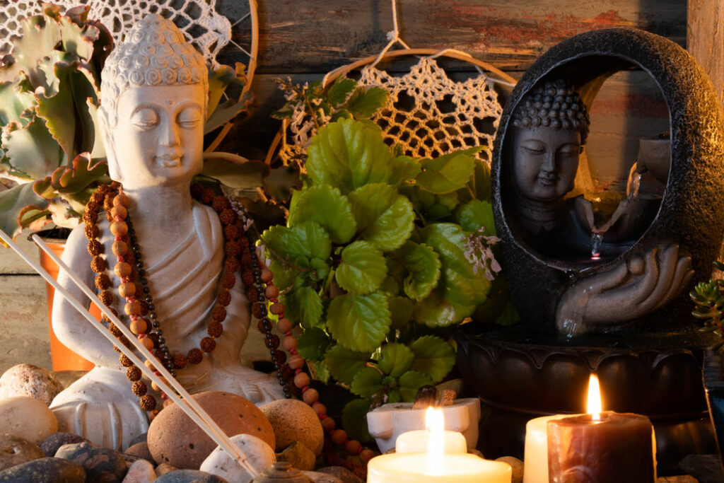 Spiritual altar with buddha statues, candles, incense, and plants.