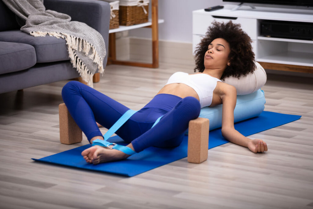 Woman practicing restorative yoga in reclined supported butterfly pose.