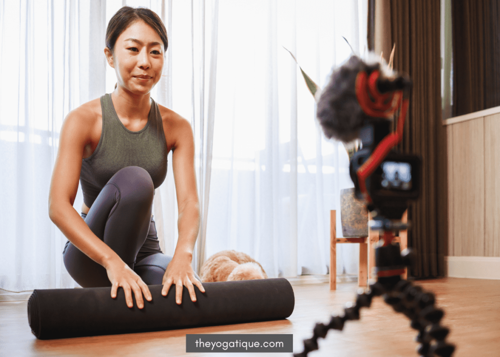 Woman teaching yoga online using a tripod camera setup and microphone.