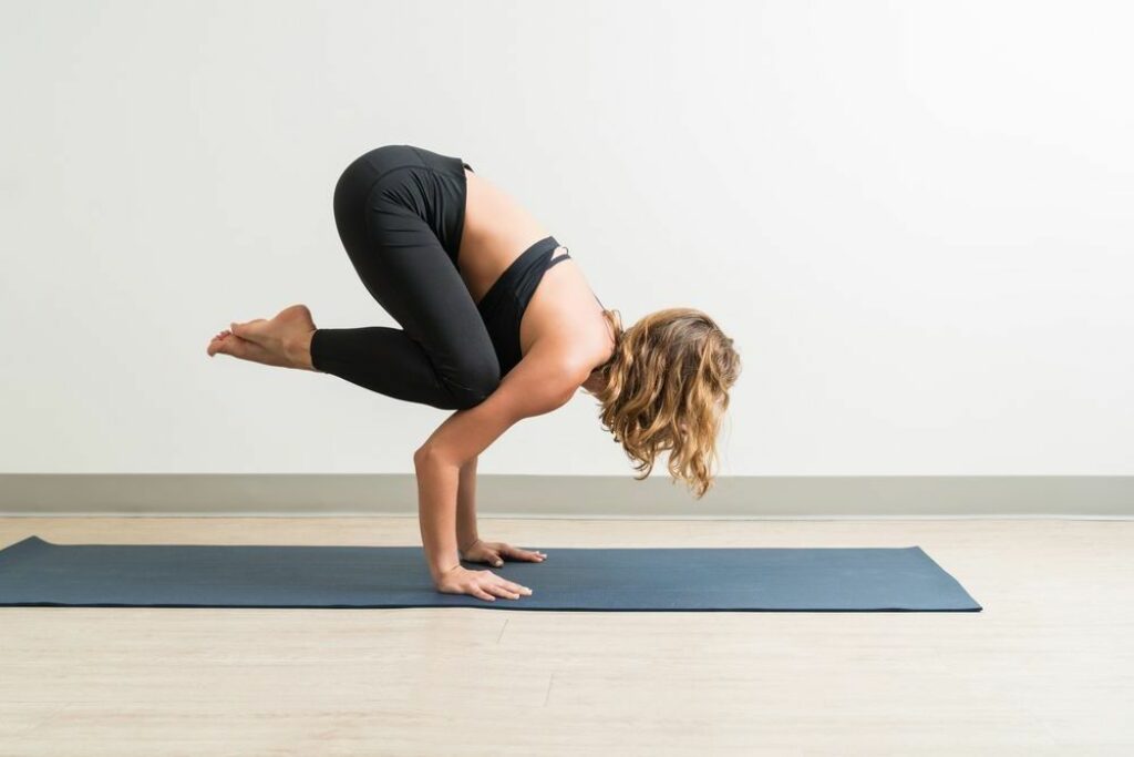 Woman doing crow yoga pose.