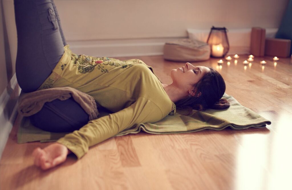 Female yogi practicing Restorative yoga in Legs up the Wall pose.