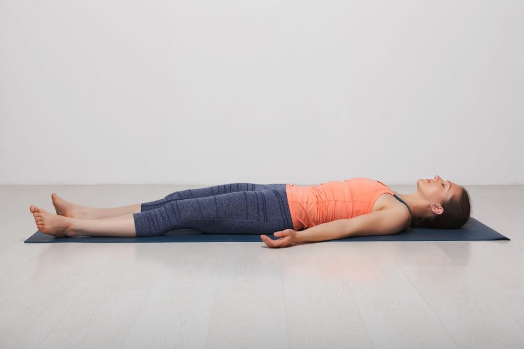 Female yogi practicing Sivananda yoga in Corpse pose.