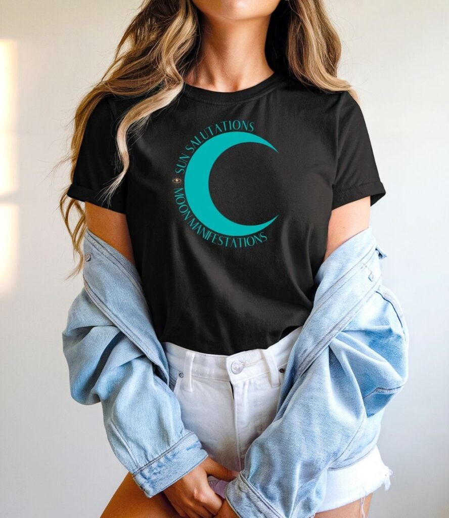 Female yogi with long hair wearing a casual black yoga graphic print t-shirt that says Sun Salutations Moon Manifestations.