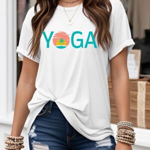 Female yogi with long hair wearing a white yoga t-shirt with a graphic print says yoga and has a sunset design.