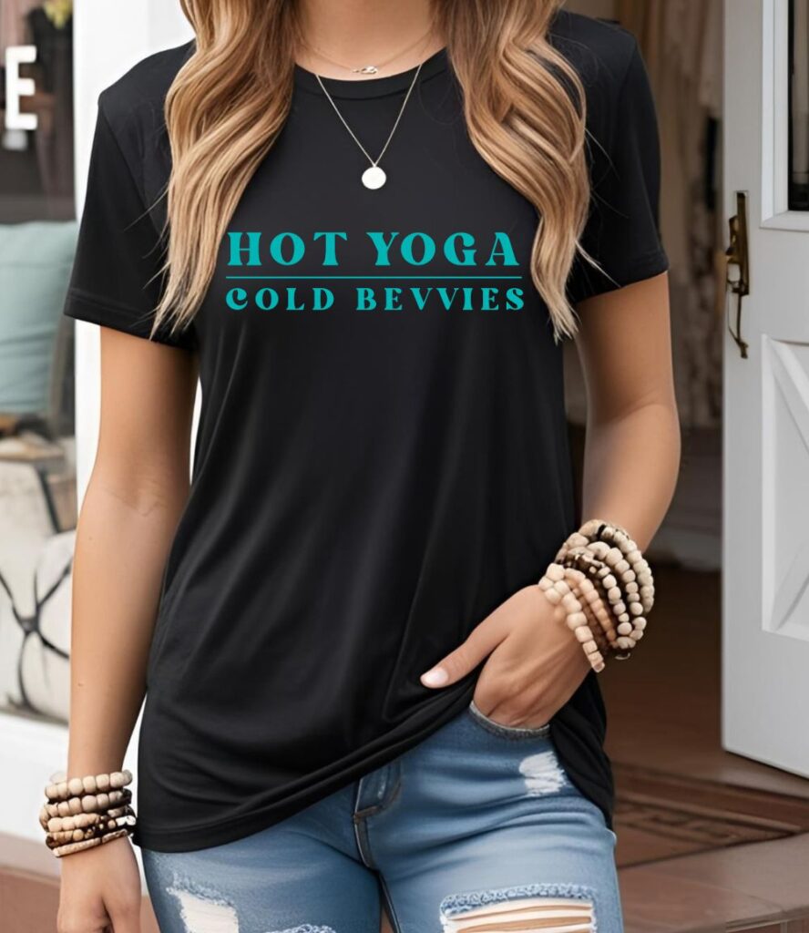Female yogi with long hair wearing a black funny yoga t-shirt with a saying that says hot yoga cold bevvies.