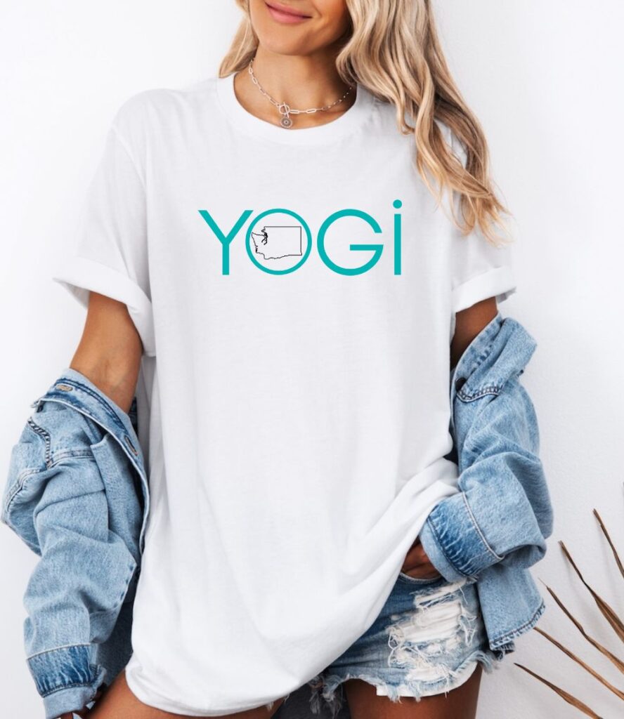 Female yogi with long hair wearing a white yoga t-shirt with a graphic of Washington State and the word yogi.