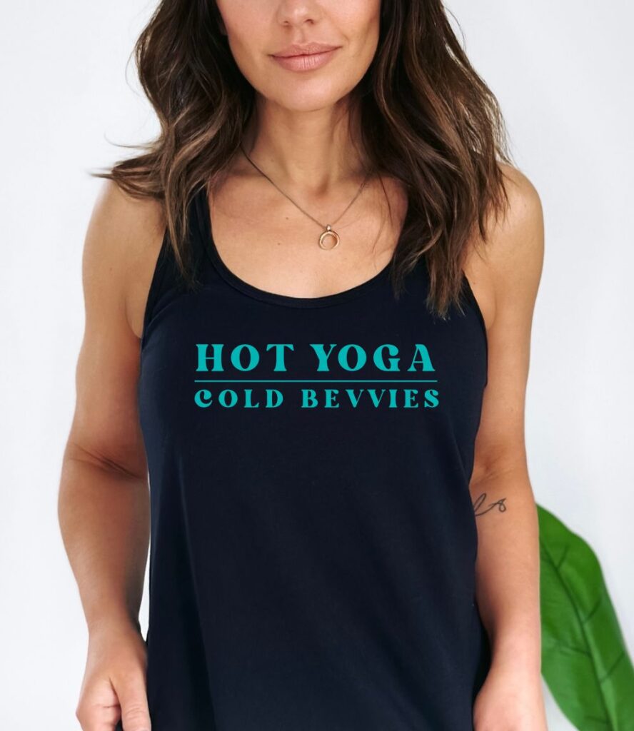 Female yogi with long brown hair wearing a black racerback yoga tank top with Hot Yoga Cold Bevvies graphic print.