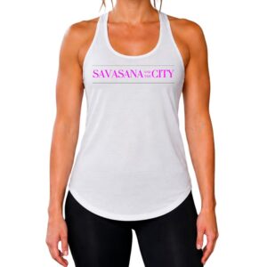Female yogi with brunette hair wearing a white racerback yoga tank top that says savasana and the city.